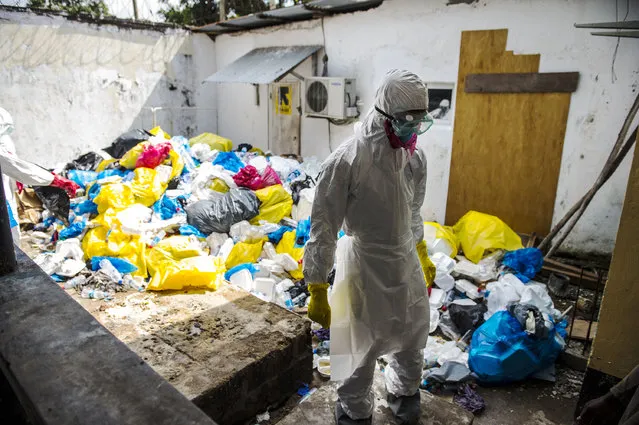 A hospital health worker stand prepares to remove garbage from Ebola patients  between wings/buildings of the Redemption  Hospital which has become a transfer and holding center to intake Ebola patients located in one of the poorest neighborhoods of Monrovia that locals call “New Kru Town” on Saturday September 20, 2014 in Monrovia, Liberia. (Photo by Michel du Cille/The Washington Post)
