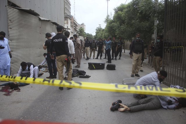 Security personnel examine the bodies of terrorists outside the Stock Exchange Building in Karachi, Pakistan, Monday, June 29, 2020. Gunmen attacked the stock exchange in the Pakistani city of Karachi on Monday. Special police forces deployed to the scene of the attack and in a swift operation secured the building. (Photo by Muhammad Ikram Suri/AP Photo)