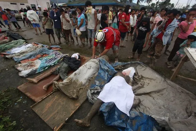 A rescuer covers bodies recovered from flashflood in New Bataan, Compostela Valley province, southern Philippines Wednesday, December 5, 2012. The death toll from Typhoon Bhopa climbed to more than 100 people Wednesday, while scores of others remain missing in the worst-hit areas of the southern Philippines. (Photo by Karlos Manlupig/AP Photo)