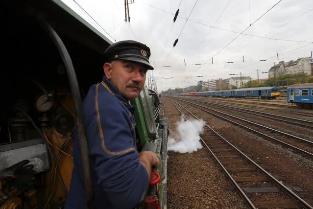 A train engineer looks out of a historic steam locomotive as it pulls a Tehran-bound train into Nyugati Terminus in Budapest, October 15, 2014. The train, a set of luxury cars retrofitted from historic models to reflect times gone by, will take two weeks to wind through the 7,000 kilometre journey across the Balkans, the Bosphorus and eastern Turkey to arrive in Iran. (Photo by Laszlo Balogh/Reuters)