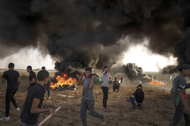 Palestinians burn tires during a protest against Israeli military raid in the West Bank, along the border fence with Israel, in east of Gaza City, Tuesday, October 25, 2022. The military says Israeli forces have raided a stronghold of an armed group in the West Bank, blowing up an explosives lab and engaging in a firefight. Palestinian health officials say five Palestinians were killed and 20 were wounded. The target of the raid was a group calling itself the Lions' Den, accused by Israel of having killed a soldier and attempting several attacks. (Photo by Fatima Shbair/AP Photo)