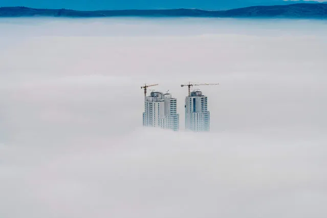 A picture taken from Vodno Mountain shows the tops of some of the city' s highest buildings above clouds in an area with a high level of air pollution in Skopje on December 15, 2017. Skopje on December 15 was affected for the second day in a row by air pollution that almost paralyzed the Macedonian capital. (Photo by Robert Atanasovski/AFP Photo)