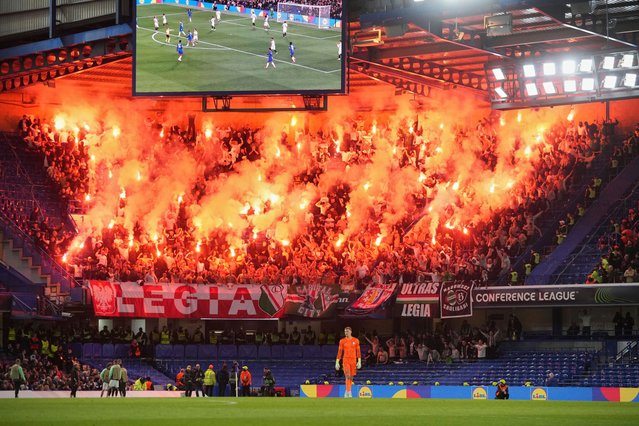 Legia supporters light flares on the stands during the Europa Conference League quarterfinals second leg soccer match between Chelsea FC and Legia Warszawa at Stamford Bridge stadium in London, Thursday, April 17, 2025. (Photo by Kin Cheung/AP Photo)