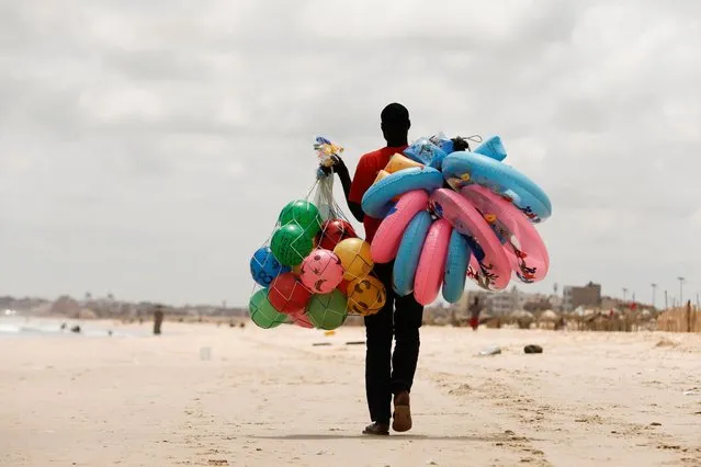 A man carries balloons and life buoys for sale on the Yoff beach, amid the outbreak of the coronavirus disease (COVID-19), in Dakar, Senegal on July 28, 2020. (Photo by Zohra Bensemra/Reuters)