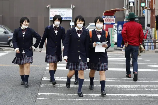 School girls, wearing surgical masks, cross a street at lunch time in Kyoto, western Japan November 19, 2014. (Photo by Thomas Peter/Reuters)