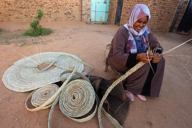 A Sudanese woman weaves palm leaves (al-Zaaf), a traditional skill of making baskets, food trays and other household items, in the village of Al-Saqqai, some 57km north of the capital Khartoum, on January 4, 2023. (Photo by Ashraf Shazly/AFP Photo)