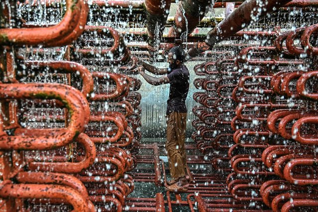 A worker cleans the lines of a cooling tower at an ice factory on a hot summer day in Karachi on May 29, 2025. (Photo by Asif Hassan/AFP Photo)