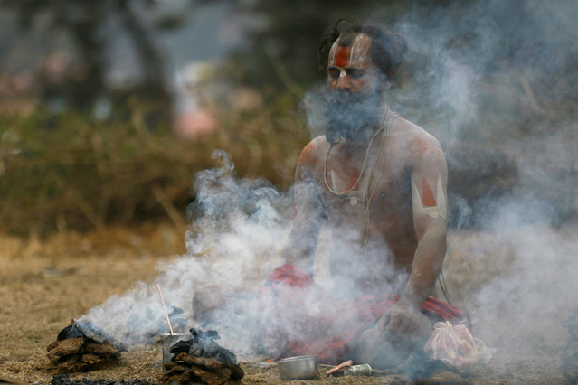 Smoke rises as a Hindu holy man, or sadhu, performs religious rituals at the premises of Pashupatinath Temple during the Shivaratri festival in Kathmandu, Nepal February 13, 2018. (Photo by Navesh Chitrakar/Reuters)