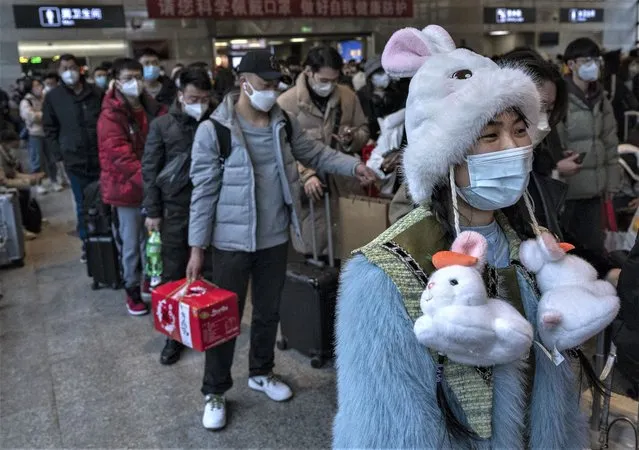 A woman wears a bunny hat for the upcoming year of the Rabbit, as she an other travellers wait to board a high speed train on their way home for the Chinese Lunar New Year and Spring Festival at Beijing West Station on January 20, 2023 in Beijing, China. Millions of Chinese travellers are headed home for the Chinese New Year of the Rabbit on January 22, the first since China dropped its strict zero Covid policy late last year. Health officials are concerned that the holiday could cause new surges of COVID-19, especially in rural areas where medical care is often less adequate than in the larger cities where officials say the outbreaks have recently peaked. (Photo by Kevin Frayer/Getty Images)