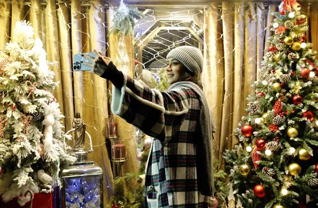 An Iranian youth takes a picture outside a shop selling Christmas trees in the capital Tehran on December 25, 2022. (Photo by AFP Photo/Stringer)