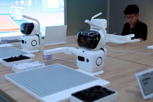 A child plays Chinese chess against a SenseRobot, a chess robot developed by SenseTime in Beijing, China on August 6, 2025. (Photo by Florence Lo/Reuters)
