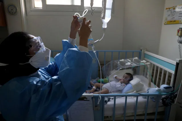 A nurse wearing a protective suit and mask tends to a baby with coronavirus at Hazrat Ali Asghar hospital in Tehran, Iran on September 27, 2020. (Photo by Wana News Agency via Reuters)