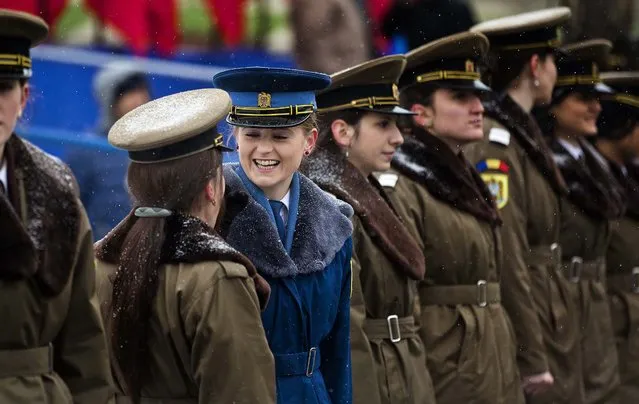 Female Romanian military personnel share a laugh before a military parade to mark Romania's national day in Bucharest, Romania, December 1, 2014. Romanians braved the cold weather to watch the traditional armed forces parade, held outside the Palace of Parliament formerly the House of the People, built during the rule of communist dictator Nicolae Ceausescu. (Photo by Vadim Ghirda/AP Photo)