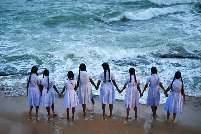 School girls hold hands while looking out at the Indian Ocean at Galle Face beach in Colombo on December 9, 2022. (Photo by Ishara S. Kodikara/AFP Photo)