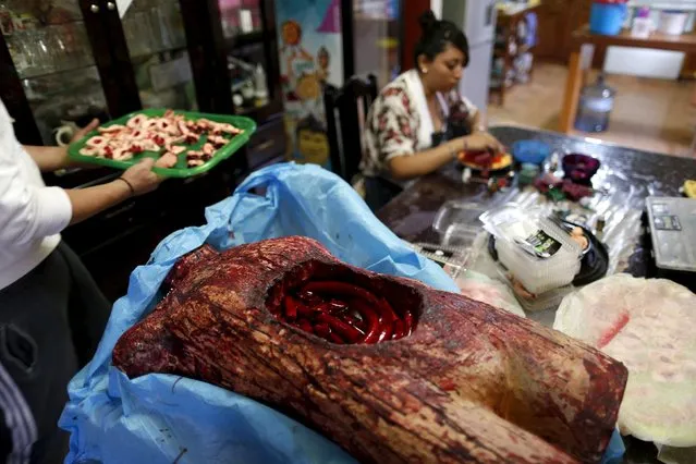 A bloody, fake open torso with jelly guts made of gummy candy is seen as a woman works at the Zombie Gourmet homemade candy manufacturer on the outskirts of Mexico City October 30, 2015. (Photo by Carlos Jasso/Reuters)