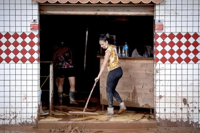A woman sweeps mud from the floor of a store after the receding of the flood in Brazilian municipality of Raposos, located in the state of Minas Gerais, on January 11, 2022, after extremely heavy rain has fallen in recent days in the southeastern part of the country. (Photo by Douglas Magno/AFP Photo)