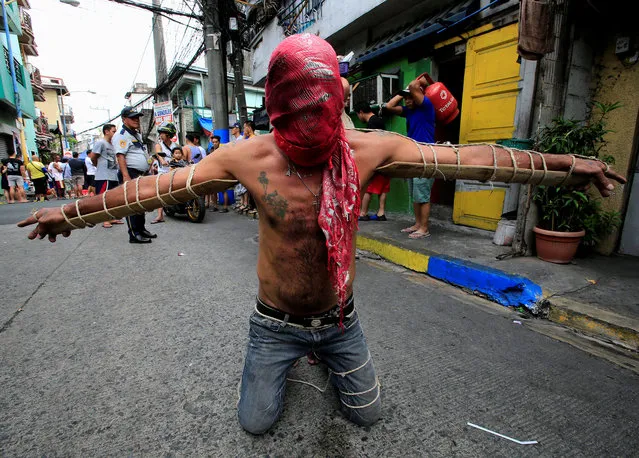 A penitent with wooden stakes tied to his arms, prays to atone for his sins during Maundy Thursdsay Lenten rites in Mandaluyong city, Metro Manila, Philippines, March 29, 2018. (Photo by Romeo Ranoco/Reuters)