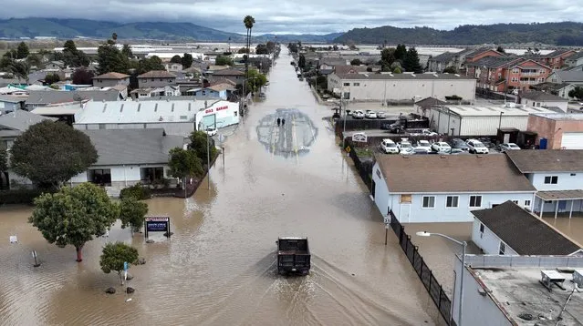 An aerial view shows a flooded neighborhood in the unincorporated community of Pajaro in Watsonville, California, on March 11, 2023. Residents were forced to evacuate in the middle of the night after an atmospheric river surge broke the Pajaro Levee and sent flood waters flowing into the community. (Photo by Josh Edelson/AFP Photo)