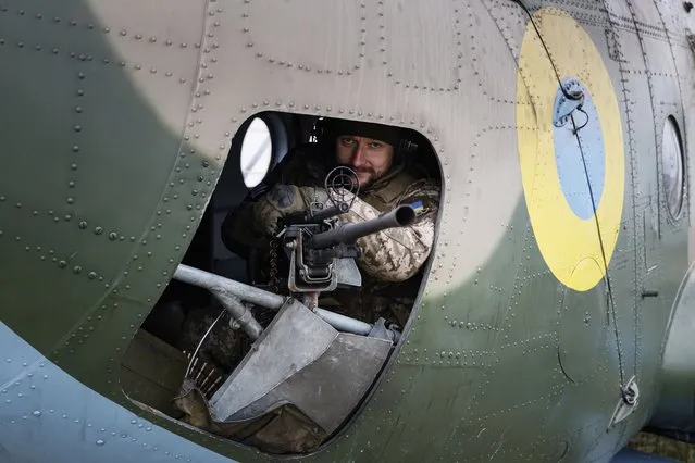 A Ukrainian serviceman of 12 aviation brigade sits inside an Mi-8 combat helicopter before flight during a combat mission in Kharkiv region, Ukraine, Sunday, April 2, 2023. (Photo by Alex Babenko/AP Photo)