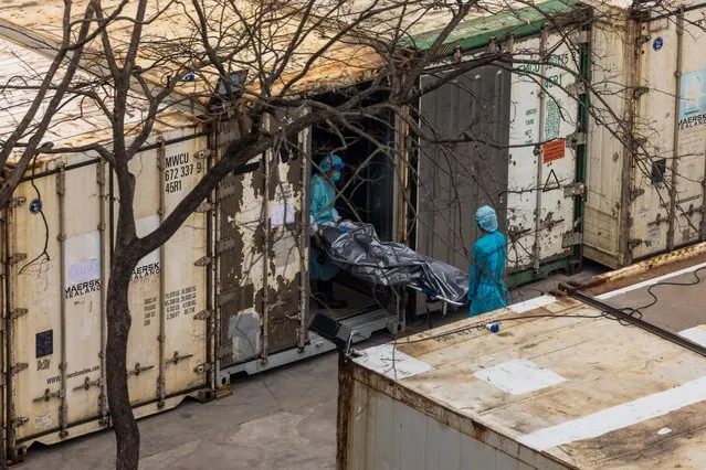 Workers move the body of deceased person from a truck into a refrigerated container at the Fu Shan Public Mortuary in Hong Kong on March 16, 2022, amid the city's worst-ever Covid-19 coronavirus outbreak that has seen overflowing hospitals and morgues and a frantic expansion of the city's spartan quarantine camp system. (Photo by Dale de la Rey/AFP Photo)
