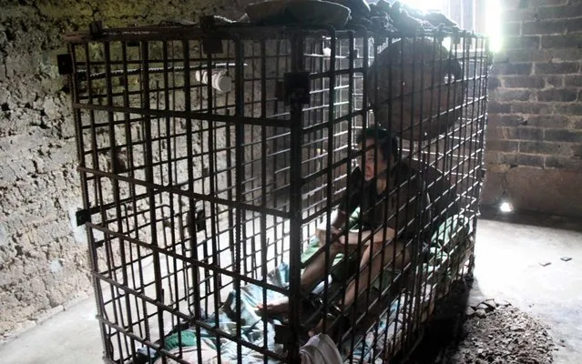 This picture taken on May 27, 2013 shows Wu Yuanhong, a mentally disabled man, sitting in his cage at his home in Lijiachong village in Ruichang, China’s Jiangxi province. Yuanhong has been locked in the cage by his parents for the past 11 years, after he allegedly beat a 13-year-old child to death, media reported. (Photo by AFP Photo)