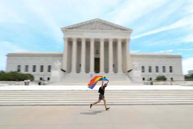 Joseph Fons holding a Pride Flag, runs in front of the U.S. Supreme Court building after the court ruled that a federal law banning workplace discrimination also covers sexual orientation, in Washington, D.C., U.S., June 15, 2020. (Photo by Tom Brenner/Reuters)