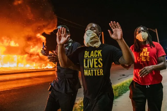 Men walk towards law enforcement with their hands up on August 24, 2020 in Kenosha, Wisconsin. A second night of civil unrest occurred after the shooting of Jacob Blake, 29, on August 23. Blake was shot multiple times in the back by Wisconsin police officers after attempting to enter into the drivers side of a vehicle. (Photo by Brandon Bell/Getty Images)