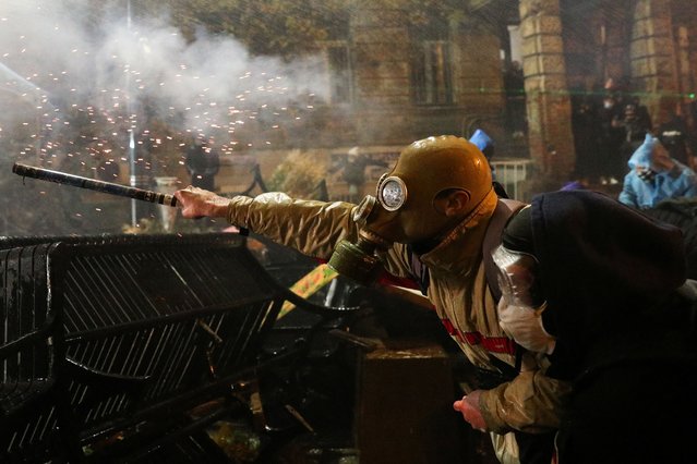 A demonstator uses fireworks during a protest against the new government's decision to suspend the European Union accession talks and refuse budgetary grants until 2028, in Tbilisi, Georgia, on December 1, 2024. (Photo by Irakli Gedenidze/Reuters)