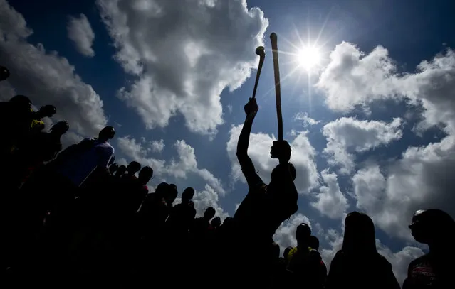 A Maasai warrior holds up his stick to line his sight, right, as he prepares to throw a Rungu, a type of wooden throwing club also known as a knobkerry, left, in a throwing competition at the annual Maasai Olympics in the Sidai Oleng Wildlife Sanctuary near to Mt Kilimanjaro, in southern Kenya Saturday, December 13, 2014. (Photo by Ben Curtis/AP Photo)