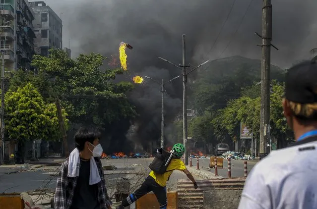 Anti-coup protesters throw molotov cocktails towards security forces in Yangon, Myanmar, Wednesday, March 17, 2021. (Photo by AP Photo/Stringer)