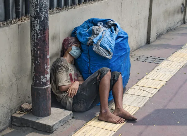 A man takes a nap on the pavement in downtown Jakarta, Indonesia on July 24, 2018. (Photo by Bay Ismoyo/AFP Photo)