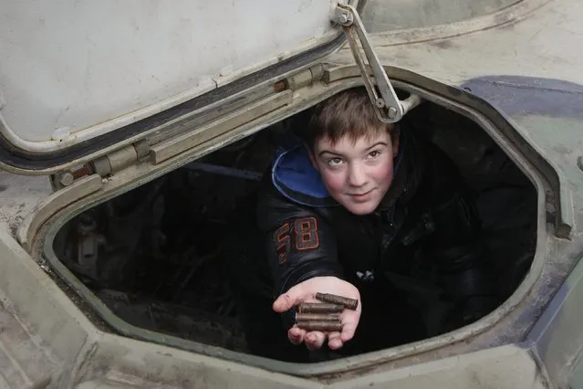 A boy shows cartridge cases found inside an armoured personnel carrier (APC) during the opening of an exhibition displaying military weapons and vehicles seized from pro-Russian separatists during fighting in eastern Ukraine, in central Kiev February 21, 2015. The exhibit shows military weapons which are of Russian origin, according to organizer Ukraine's Presidential Administration. REUTERS/Valentyn Ogirenko  (UKRAINE - Tags: CIVIL UNREST MILITARY)