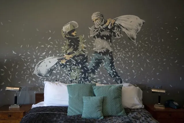 A Banksy wall painting showing Israeli border policeman and a Palestinian in a pillow fight is seen in one of the rooms of the The Walled Off Hotel in the West Bank city of Bethlehem, Sunday, June 19, 2022. Despite the roaring return of travelers, challenges and uncertainty cast shadows over the post-pandemic landscape. Full recoveries are generally not expected until at least 2024. (Photo by Maya Alleruzzo/AP Photo)