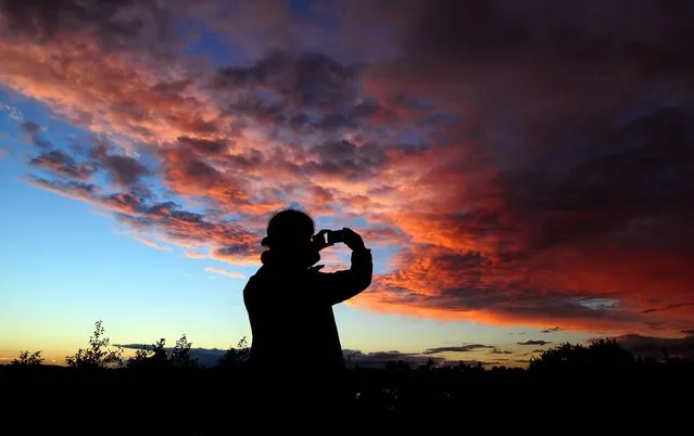 A person uses a phone to capture a  sunset sky in South Derbyshire, on October 19, 2013. (Photo by Rui Vieira/PA Wire)