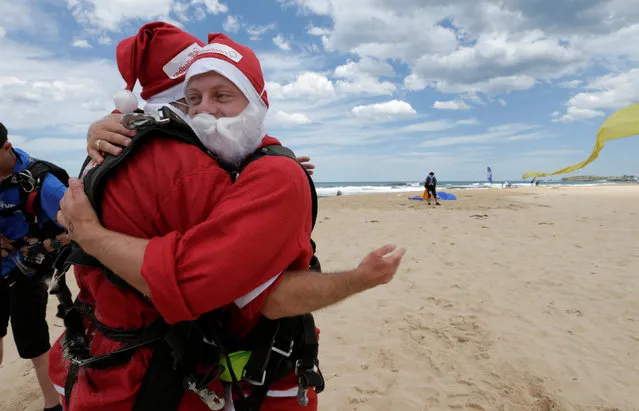 Tandem skydivers Stuart Smith (R) and Sebastian Terry hug after they landed on a beach as 155 skydives sets a new Guinness World Record number tandem skydivers over eight hours in the Australian city of Wollongong, December 17, 2016. (Photo by Jason Reed/Reuters)