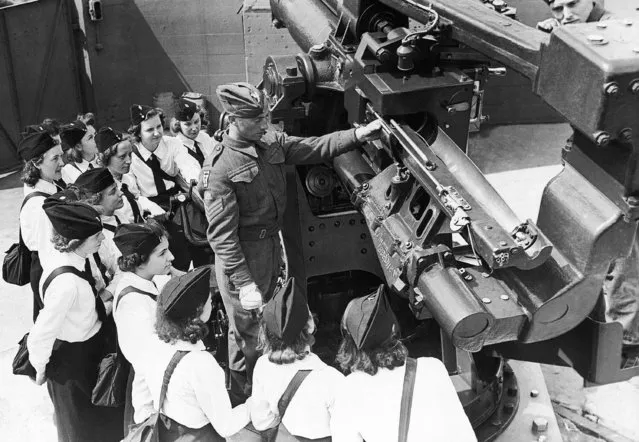 One of the soldiers stationed at this gun site shows the G.T.O. girls how the anti-aircraft gun is worked in England on May 21, 1942. (Photo by AP Photo)