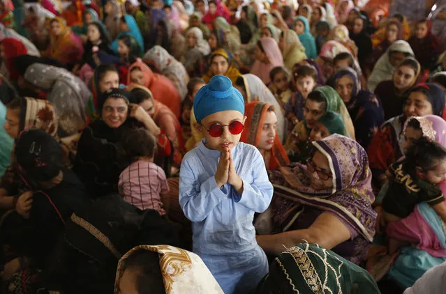 A Sikh child stands beside his mother attending a ceremony to observe the Martyrdom Day of Guru Arjan Dev Ji, at Gurudwara Dera Sahib, in Lahore, Pakistan, Wednesday, June 16, 2021. Hundreds of Sikh pilgrims are attending the 415th anniversary of the death of the fifth Sikh Guru, Arjan Dev Ji, that is celebrated in Derah Sahib. (Photo by K.M. Chaudary/AP Photo)