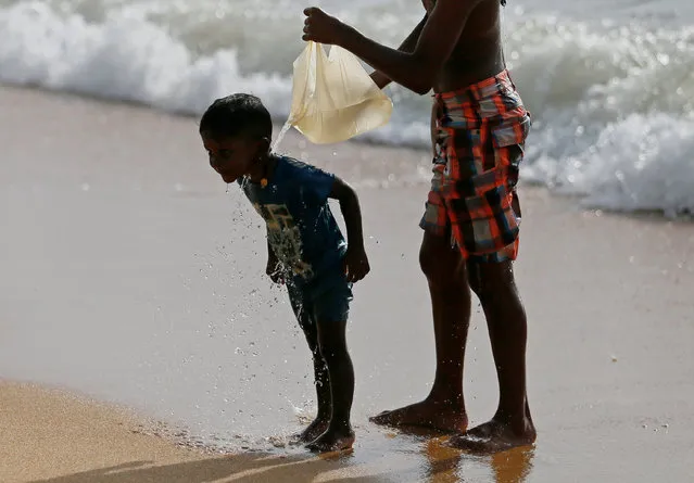 A boy bathes another boy with sea water collected in a plastic bag on a beach in Colombo, Sri Lanka November 23, 2016. (Photo by Dinuka Liyanawatte/Reuters)