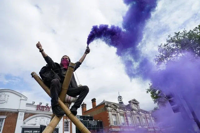 A demonstrator holds a flare in Windrush Square during the annual Afrikan Emancipation Day Reparations march in London, Sunday, Aug. 1, 2021, Black people whose right to live in the U.K. was illegally challenged by the government marked the anniversary Sunday of the act that freed slaves throughout the British Empire, drawing a direct link between slavery and the discrimination they suffered. Dozens of campaigners gathered in Brixton, a center of the Black community in south London, to back the international drive for reparations for the descendants of enslaved Africans and demand legislation to compensate legal residents who were threatened with deportation in what is known as the Windrush Scandal. (Photo by Alberto Pezzali/AP Photo)