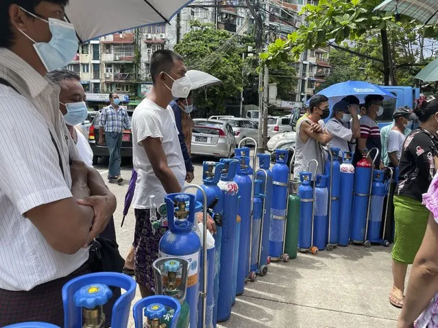 People queue up with their oxygen tanks outside an oxygen refill station in Pazundaung township in Yangon, Myanmar, Sunday, July 11, 2021. Myanmar is facing a rapid rise in COVID-19 patients and a shortage of oxygen supplies just as the country is consumed by a bitter and violent political struggle since the military seized power in February. (Photo by AP Photo/Stringer)