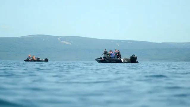 In this handout photo taken from video released by Kamchatka regional government, emergency personnel work near the site where a helicopter carrying tourists crashed at Kurile Lake in the Kronotsky nature reserve on the Kamchatka Peninsula in Russia, Thursday, August 12, 2021. A helicopter carrying tourists has crashed into a deep volcanic crater lake on the Kamchatka Peninsula in Russia's far east, leaving up to eight people missing. Officials said at least eight survived. Emergency workers including divers were searching for survivors in Kurile Lake in the Kronotsky nature reserve. (Photo by Kamchatka regional government via AP Photo)
