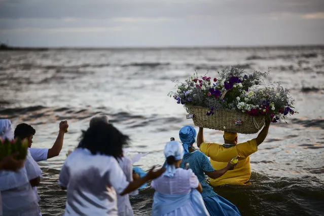 A priest of the Afro-American Umbandista cult launches a basket with offerings into the sea to Iemanja, the African goddess of the sea, at Ramirez beach in Montevideo on February 2, 2019. Thousands of worshippers and onlookers crowd the beaches throughout the Uruguayan coast to mark the celebration of the deity. (Photo by Ronaldo Schemidt/AFP Photo)