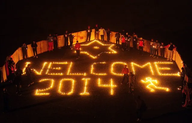 Indian sports players from the Madan Mohan Malviya Stadium light candles during an event to welcome the New Year in Allahabad on December 31, 2013. People around the world are welcoming 2014. (Photo by Sanjay Kanojia/AFP Photo)