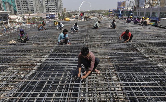 Workers fasten iron rods together at the construction site of a flyover on the outskirts of Ahmedabad, India, February 26, 2016. (Photo by Amit Dave/Reuters)