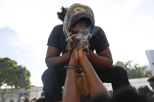 A voodoo believer possessed with a Gede spirit performs a cleansing for a woman during Day of the Dead celebrations at the National Cemetery in Port-au-Prince, Haiti, Wednesday, November 1, 2023. Followers of Vodou are marking the Fete Gede celebration of the spirits, equivalent to the Roman Catholic festival of All Saints Day. (Photo by Odelyn Joseph/AP Photo)