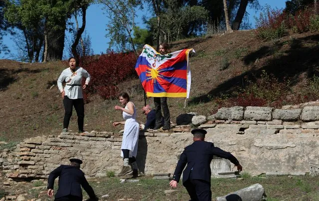 Security officers stop three protesters holding a banner and a Tibetan flag as they crash the flame lighting ceremony for the Beijing 2022 Winter Olympics at the Ancient Olympia archeological site, birthplace of the ancient Olympics in southern Greece on October 18, 2021. (Photo by Costas Baltas/Reuters)
