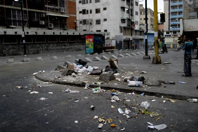 Garbage lays scattered on the pavement in Caracas, Venezuela, early Monday, March 25, 2019. The poor and hungry scour through household trash, scattering it across street corners before it's collected, grabbing anything they can use or eat. (Photo by Natacha Pisarenko/AP Photo)