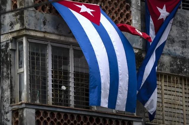 Cuban flags drape the windows of the home of Yunior Garcia Aguilera, which block his windows and prevent his communicating with the outside, in Havana, Cuba, Monday, November 15, 2021. Garcia, one of the organizers of a banned opposition march, is a member of the internet debate forum Archipiélago which Cuban authorities considers illegal. (Photo by Ramon Espinosa/AP Photo)