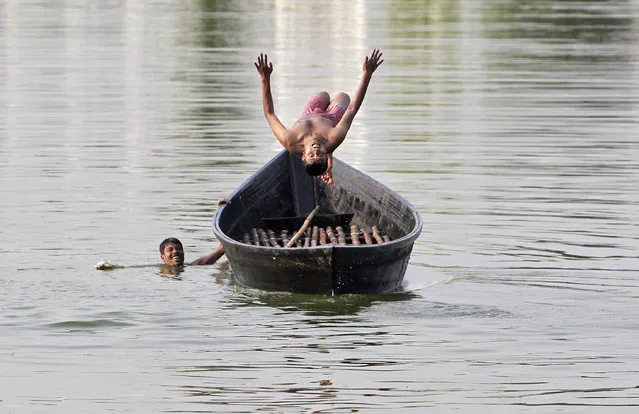 A boy jumps from a boat into Laxmi Narayan Lake to cool off in Agartala, India, March 22, 2016. (Photo by Jayanta Dey/Reuters)