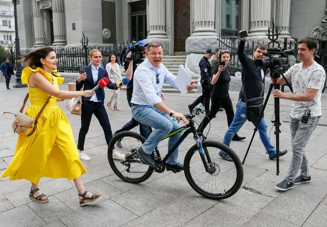 Radical Party leader Oleh Lyashko speaks with journalists as he rides a bicycle after new President Volodymyr Zelenskiy held consultations with lawmakers, near the Presidential Administration headquarters in Kiev, Ukraine on May 21, 2019. (Photo by Gleb Garanich/Reuters)